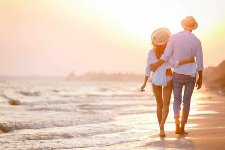 Glückliches Paar spaziert am Strand in der Sonne