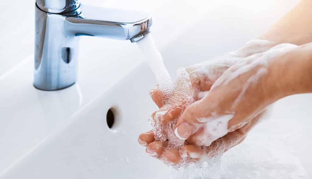 Frau wäscht Hände im Waschbecken mit Seife
